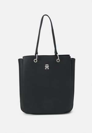 Sac fourre-tout en cuir noir avec deux longues poignées et un petit logo en métal argenté au centre avant.