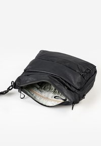 Borsa a tracolla compatta nera con scomparto principale con zip aperto, che mostra l'interno in tessuto grigio e una piccola tasca con zip all'interno.