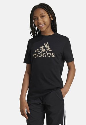 Camiseta de algodón negra con un gran logo de Adidas en print de leopardo beige y marrón oscuro en el frente. Mangas cortas, cuello redondo.