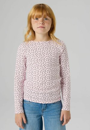 Langärmliges rosa Oberteil mit schwarzen Punkten, gerippter Textur und rundem Ausschnitt. Kombiniert mit blauen Jeans.