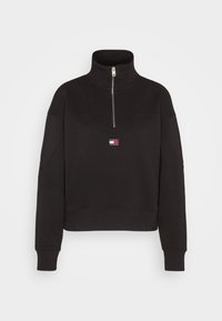 Felpa nera con colletto alto e zip a quarti, caratterizzata da una patch del logo a contrasto e polsini e orlo a coste. Texture liscia.
