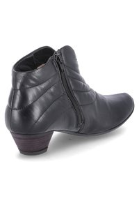 Botín de piel negra con cremallera lateral, con detalles de patrón cosido y un bajo tacón de madera. Textura suave y punta afilada.