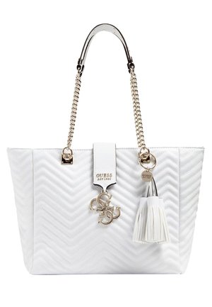 White quilted handbag with gold chain handles, gold Guess logo charm, and white tassel keychain detail.