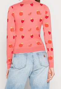 Maglione lavorato a maglia di colore rosa con colletto a coste. Presenta motivi ricamati di fragole rosse e fette d'arancia. Forma aderente.