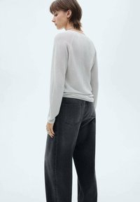 Lichtgrijze gebreide trui met lange mouwen, gecombineerd met hoge taille en brede zwarte denim jeans, met achterzakken en een losse pasvorm.