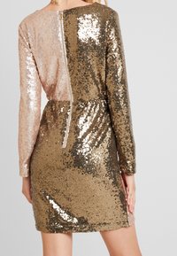 Robe à manches courtes ornée de sequins présentant un design en blocs de couleur rose et or, avec une fermeture éclair au dos et une taille cintrée pour une silhouette ajustée.