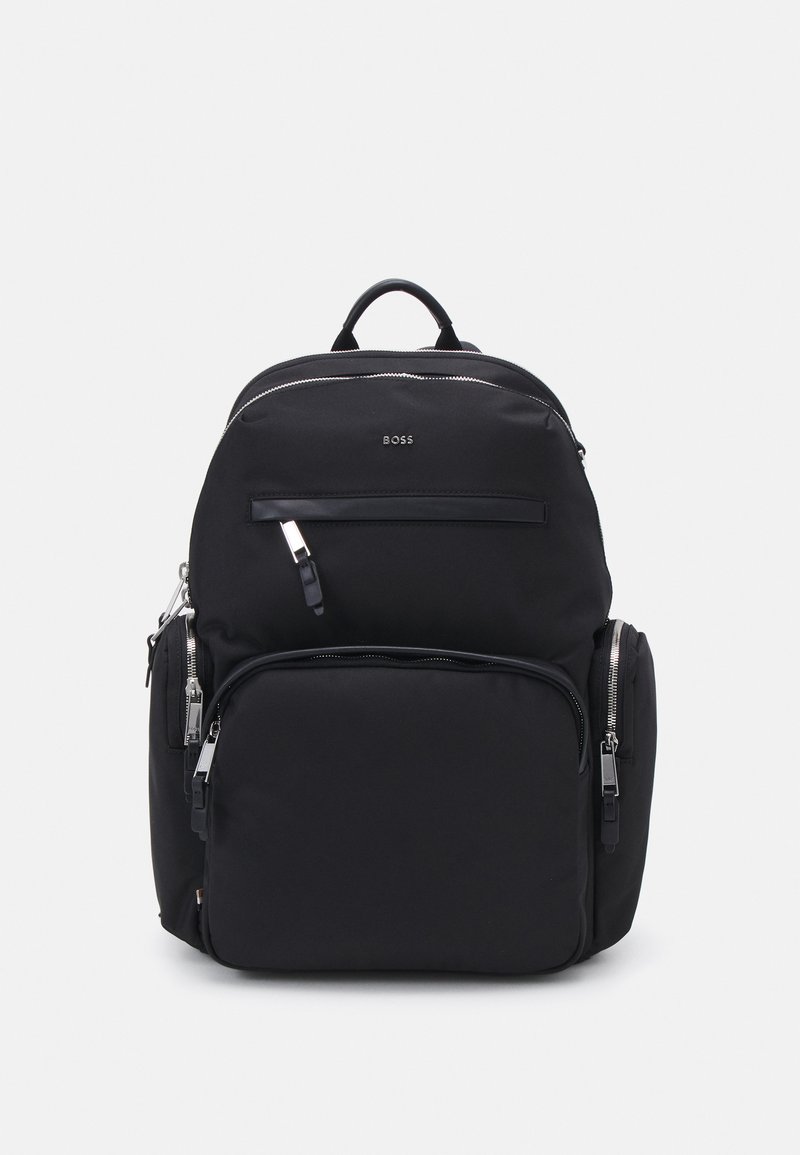 Sac à dos en nylon noir avec une texture lisse, des compartiments zippés, un logo bien en vue, des bretelles ajustables et une poignée supérieure pour plus de commodité.