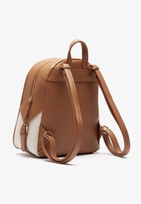 Mochila de imitación cuero marrón con forma redondeada, cierre de cremallera y acentos de malla beige clara. Correas ajustables y detalles en hardware dorado.