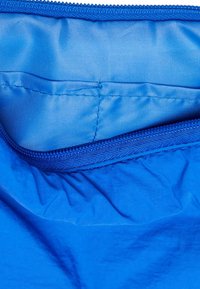 Borsa di stoffa blu con una texture liscia, caratterizzata da un colore uniforme e una chiusura a zip sulla parte superiore. L'interno è foderato con un materiale blu coordinato.