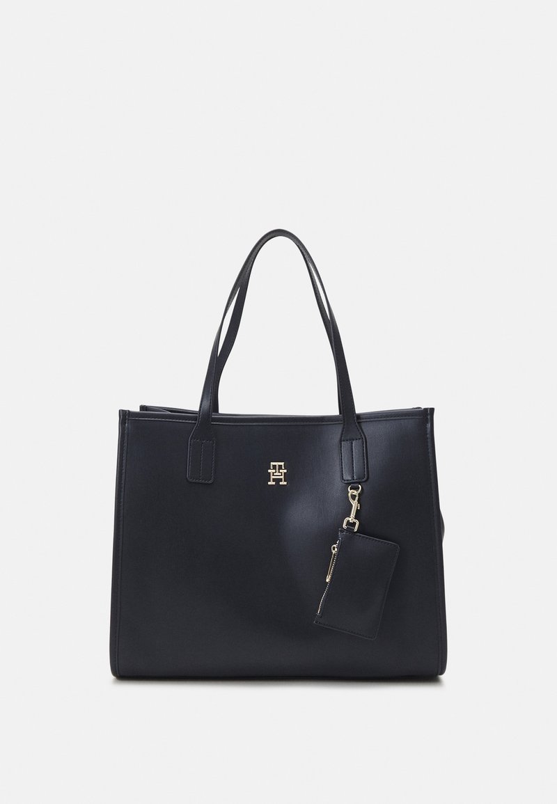 Sac cabas en cuir noir avec deux anses, petite pochette attachée et un logo doré au centre devant.