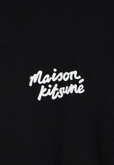 Melna kokvilnas T-kreklu ar baltu skriptu logotipu, "maison kitsuné," centrā izvietots. Gluda tekstūra ar klasisku apaļu kakla dizainu.