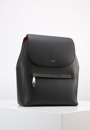 Zaino in pelle nera con chiusura a patta, tasca frontale con cerniera dorata e piccolo logo "RLL" dorato su una superficie bianca.