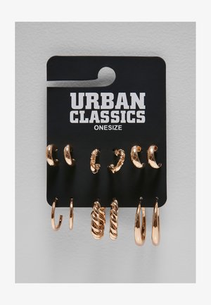 Ensemble de six paires de boucles d’oreilles créoles dorées de styles variés, présentées sur une carte noire de la marque Urban Classics libellée onesize.
