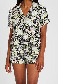 Floral print short-sleeve button-up shirt and matching shorts, featuring black background, light pastel colors, and a loose fit.