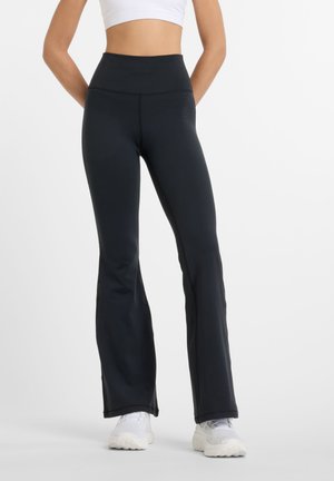 Leggings neri a gamba flared realizzati in un tessuto elastico e morbido, con una vita alta e cuciture decorative lungo i lati.