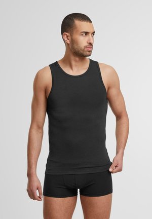Canottiera nera in un design aderente con scollo rotondo. Tessuto morbido e liscio. Indossata con boxer neri abbinati.