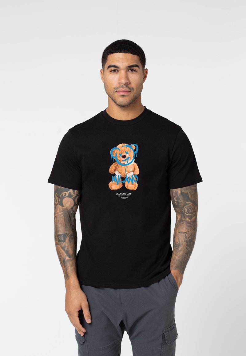 Black cotton t-shirt featuring a cartoon bear graphic in orange and blue, with the text "MILANO." Includes short sleeves and a crew neckline.