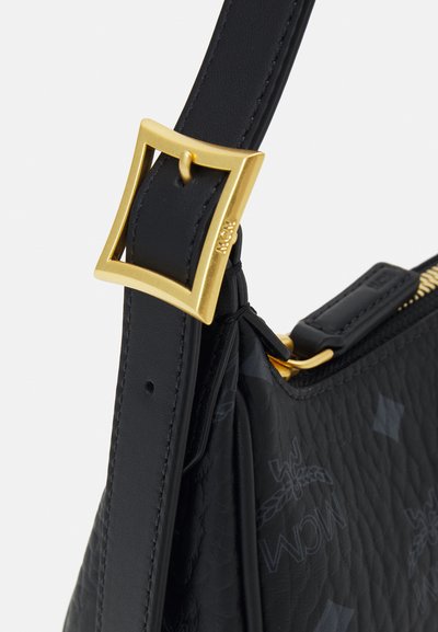 Schwarze Lederhandtasche mit strukturiertem Finish, goldenen quadratischen Beschlägen und einem abnehmbaren Trageriemen. Die Tasche hat subtile Branding-Details.