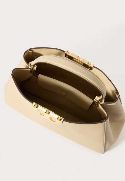 Beige leren handtas met een gladde textuur, goudkleurige hardware en een gestructureerde vorm. Het interieur is ruim met één zak.