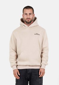 Sudadera de color beige claro con bolsillo frontal, capucha con cordón, puños acanalados y dobladillo. Presenta un logo bordado en el área del lado izquierdo del pecho.
