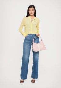 Yellow knit cardigan, blue wide-leg jeans, pink leather handbag, heeled brown sandals; smooth textures and casual design details.