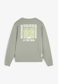 Lichtgroen sweatshirt met lange mouwen. Kenmerkt zich door een grafische print op de achterkant met "SCALPERS" en een zonnestralenontwerp. Geribde manchetten en zoom.