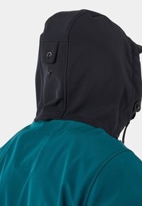 Giacca con cappuccio che presenta un cappuccio nero e un corpo teal. Il materiale appare liscio con cuciture visibili e bottoni sul cappuccio per la regolazione.