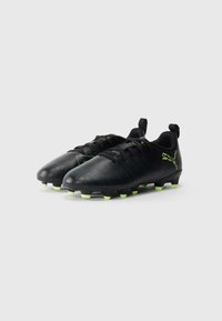 Pár čiernych futbolových kopačiek s neonovo zelenými kolíkmi a logom Puma, pohľad z predného uhla na bielom pozadí.
