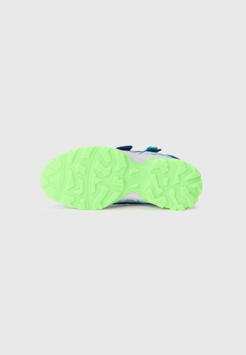Grüne strukturierte Sohle eines Kindersneakers mit blauen, weißen und schwarzen oberen Teilen, vor einem weißen Hintergrund gezeigt.