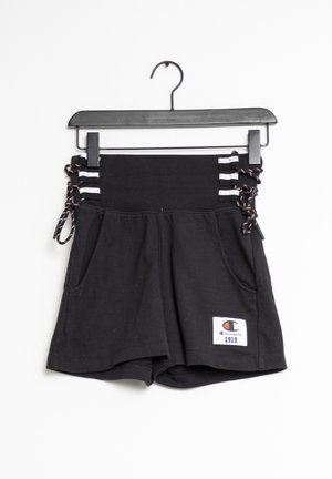 Schwarze Shorts mit hoher Taille und seitlichen Schnürdetails, weißen Streifen, Vordertaschen und einem Champion 1919 Logoaufnäher am Saum, hängend an einem schwarzen Kleiderbügel.