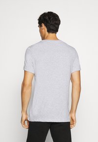 Camiseta gris de manga corta con cuello redondo, hecha de una tela suave, con un diseño simple y un corte relajado. Vista trasera lisa.