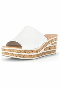 Sandales à talon en wedge ouvertes sur l'avant, blanches, avec une semelle en liège texturée. Le design présente des rainures horizontalement et une partie supérieure lisse et courbée.