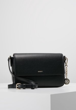Zwarte leren crossbody tas met verstelbare band, gouden DKNY-logo en een ronde metalen bedel aan de zijkant.
