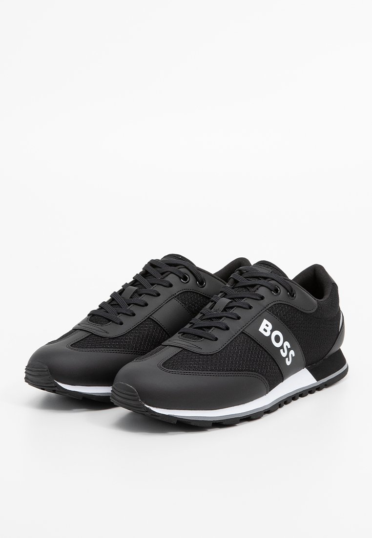 Para czarnych niskich sneakersów z siateczkowo-skórzanym wzorem, białą taśmą na śródpodeszwie i logo "BOSS" z boku.