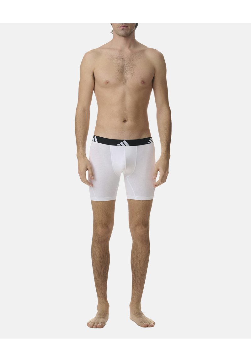 Weiße Baumwoll-Boxershorts mit einem schwarzen elastischen Bund, der ein Logo trägt, und einem engen Design, das bis zur Mitte des Oberschenkels reicht.