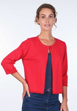 Red knitted cardigan with three-quarter sleeves, scalloped hem, and embroidered details on sleeves, paired with a navy top.