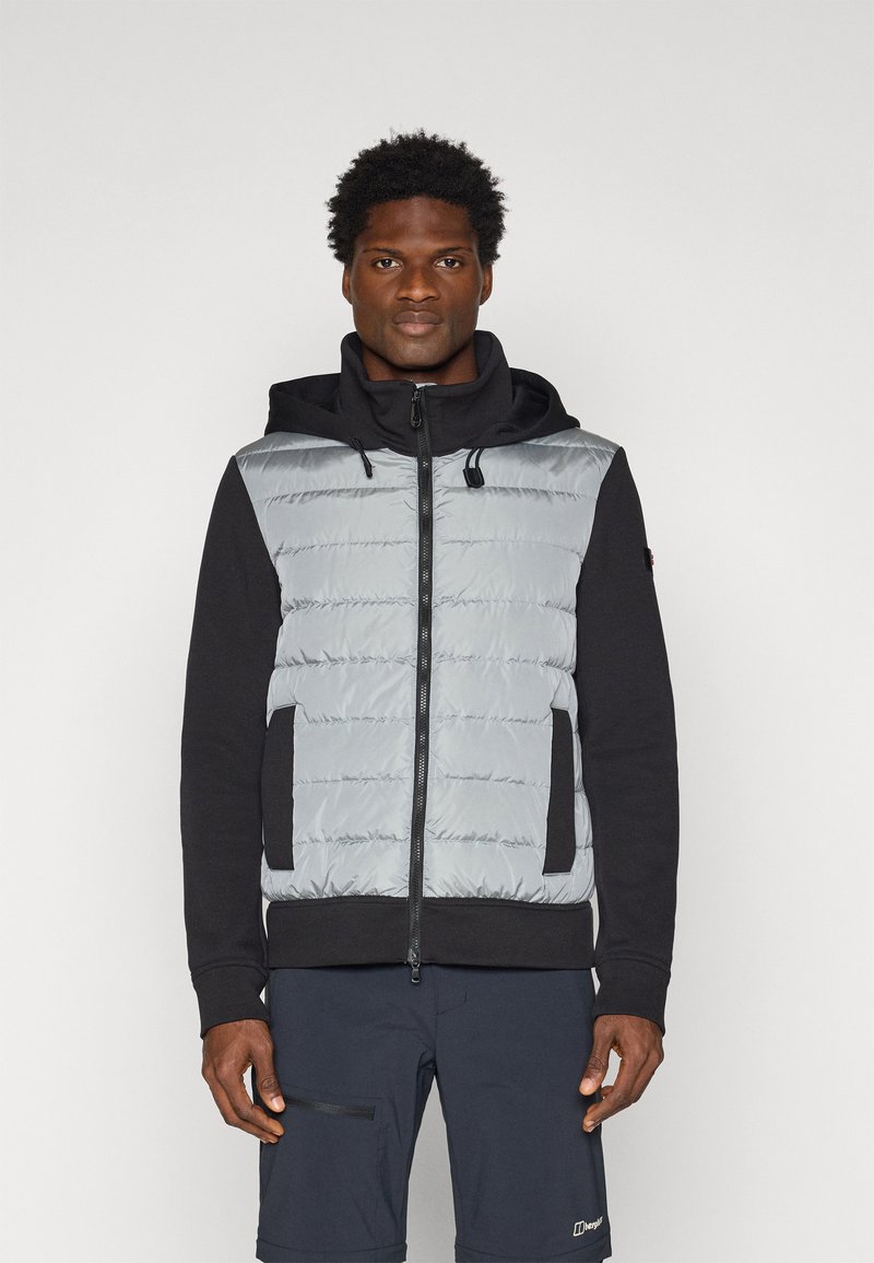 Wypełniona kamizelka w jasnoszarym kolorze z zapięciem na zamek i czarnymi akcentami. Wyposażona w kaptur i boczne kieszenie, wykonana z mieszanki materiałów syntetycznych.