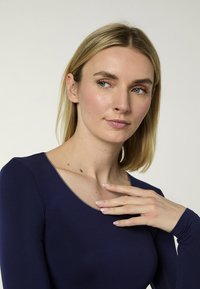 Marineblaues Langarm-Top mit hellgrauem Halsausschnitt, glatter Textur, figurbetontem Design, das einen runden Kragen und einen passenden Hautton zeigt.