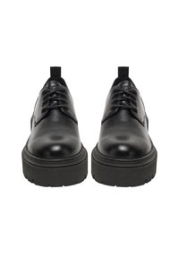 Zapatos negros de cuero con punta redondeada, textura lisa y suela gruesa de goma. Cuentan con cordones y tiradores en el talón para facilitar su uso.