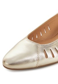 Zapato plano de color dorado hecho de cuero metálico, con punta puntiaguda, recortes laterales y textura suave.