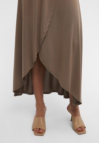 Brun asymmetrisk kjole med en blød tekstur, der har en høj-lav kant og lagdelt design. Båret med beige åbne tå mules.