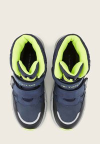 Marineblauwe hoge sneakers met neon groene voering, voorzien van verstelbare riemen, een gepolsterde kraag en textuurmaterialen. Transparante rubberen zool.