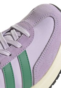 Fialové tenisky s zelenými koženými akcentmi, s textúrovaným semišom a hladkým textilom. Obsahuje biele šnúrky a gumenú podrážku.