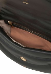 Zwarte leren handtas open om een lichtbruine ritszak binnenin te tonen en een gouden magnetische sluiting op de klep.