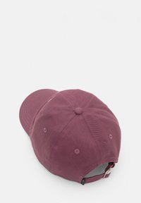 Casquette bordeaux avec une visière arrondie, texture en tissu, design à six panneaux, œillets de ventilation et sangle ajustable à l'arrière.