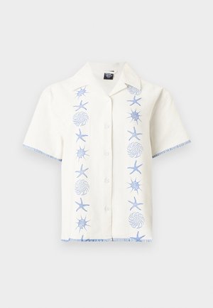 Λευκό πουκάμισο με κοντά μανίκια και κουμπιά, με μπλε κεντητά θαλάσσια αστέρια, κοχύλια και ραμμένα περιθώρια στα μανίκια και το τελείωμα.