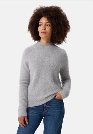Maglione grigio chiaro e morbido con maniche lunghe e scollatura rotonda, abbinato a jeans in denim blu; texture soffice e vestibilità rilassata.
