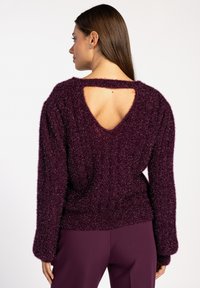 Paarse fuzzy trui met een open rugontwerp. Gebreide textuur, losse pasvorm en lange mouwen. Lagere zoom met geribde manchetten.