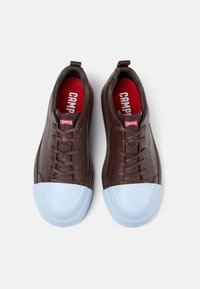 Brown leather sneakers with a rounded light blue rubber toe cap, featuring red interior lining and a small red logo tag on the tongue.