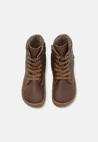 Bruine leren enkellaarzen met een gestructureerde afwerking, imitatiebont voering en platte veters. Voorzien van een afgeronde neus en rubberen zolen.